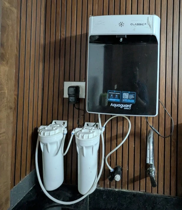 Wall-mounted Aquaguard Select Classic Plus water purifier with dual pre-filters in the Riverside Retreat homestay kitchen, ensuring 100% safe drinking water for guests.